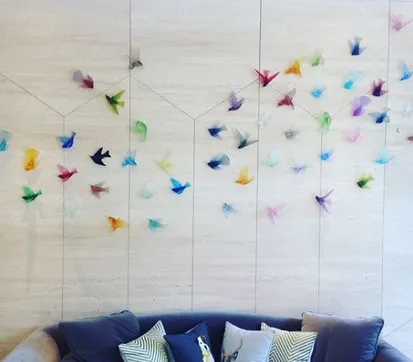 Colourful handcrafted glass birds displayed together as a memorial installation